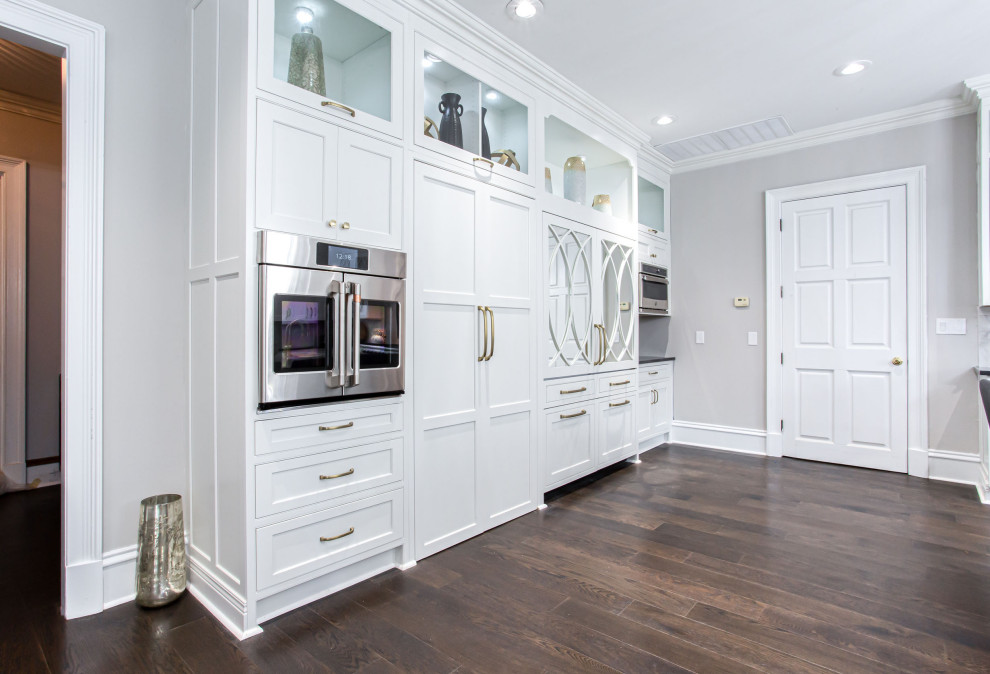 Inspiration for an expansive transitional u-shaped open plan kitchen in Atlanta with an undermount sink, beaded inset cabinets, white cabinets, quartzite benchtops, multi-coloured splashback, marble splashback, panelled appliances, medium hardwood floors, multiple islands, brown floor and white benchtop.