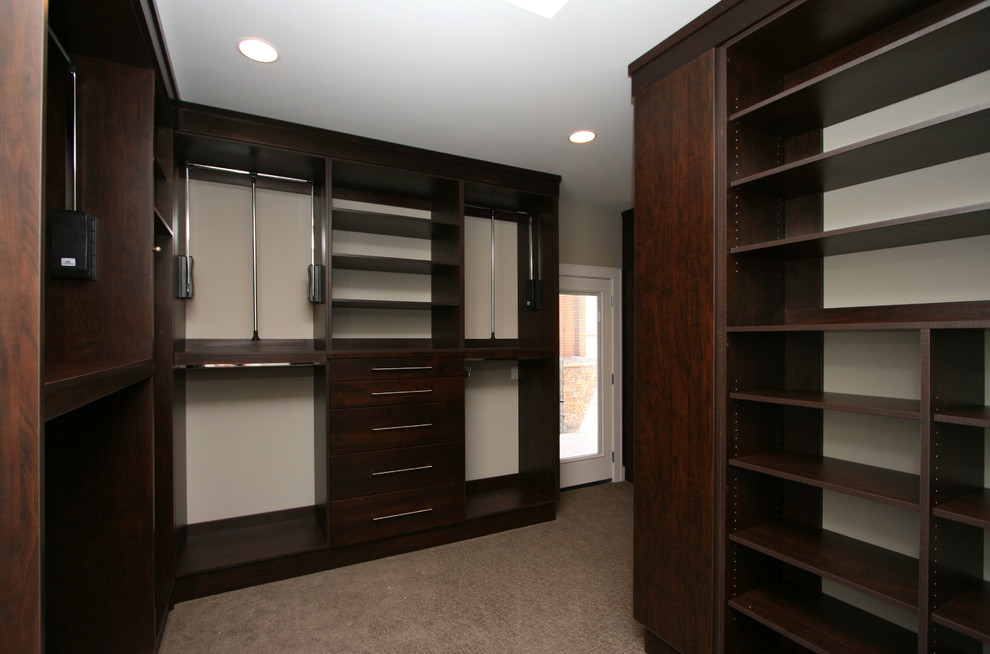 Inspiration for a mid-sized contemporary gender-neutral walk-in wardrobe in Seattle with flat-panel cabinets, dark wood cabinets and carpet.