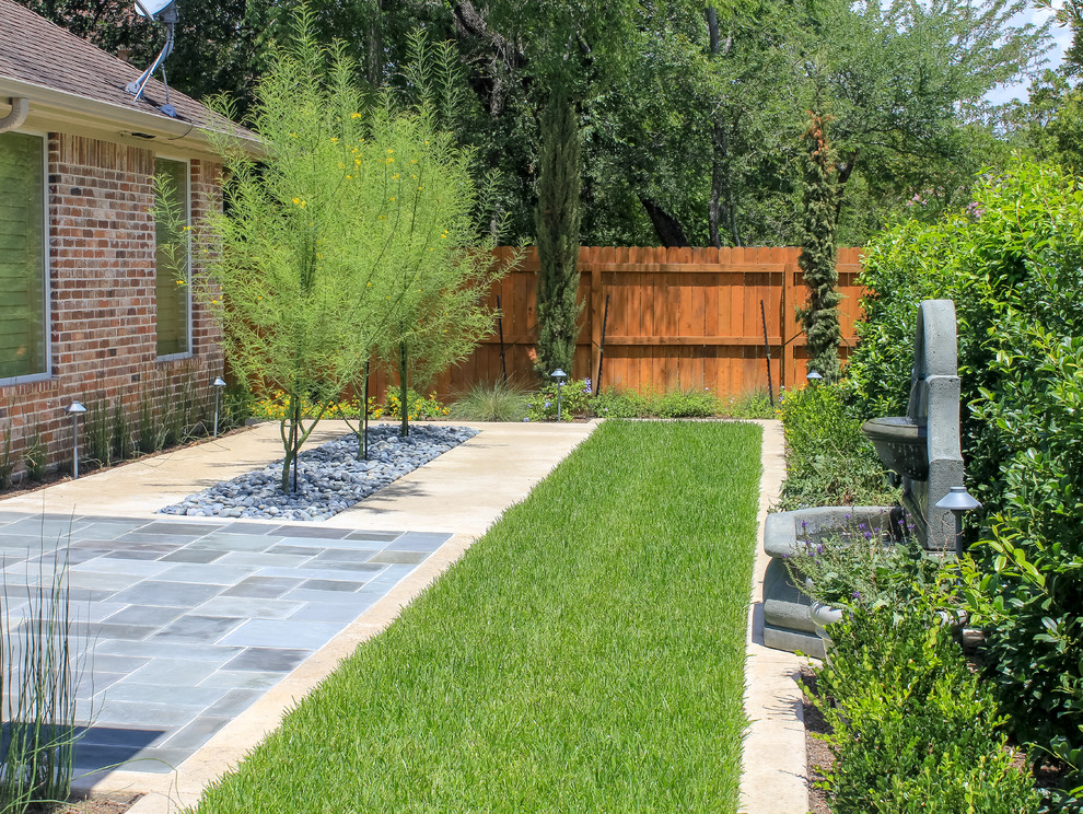 This is an example of a small contemporary backyard full sun formal garden for spring in Dallas with a water feature and natural stone pavers.