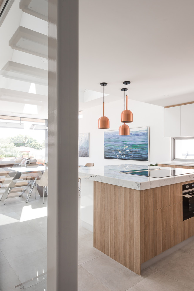 Design ideas for a contemporary l-shaped open plan kitchen in Perth with an undermount sink, light wood cabinets, marble benchtops, black appliances, ceramic floors, with island, grey floor, white benchtop, flat-panel cabinets and window splashback.