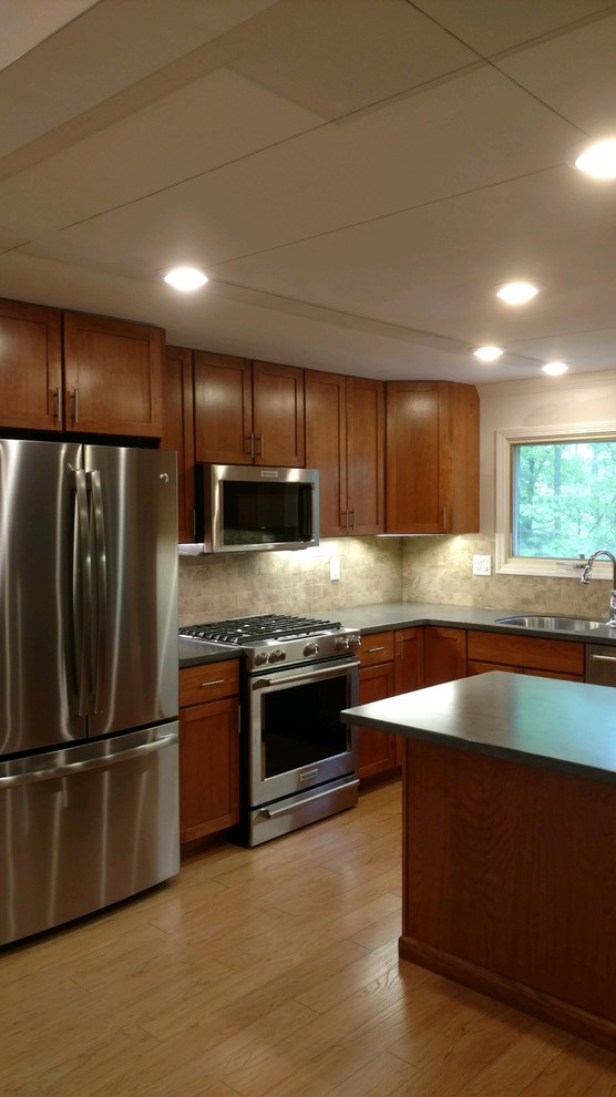 Photo of a modern kitchen in New York with an undermount sink, shaker cabinets, solid surface benchtops, beige splashback, ceramic splashback, stainless steel appliances, with island and grey benchtop.