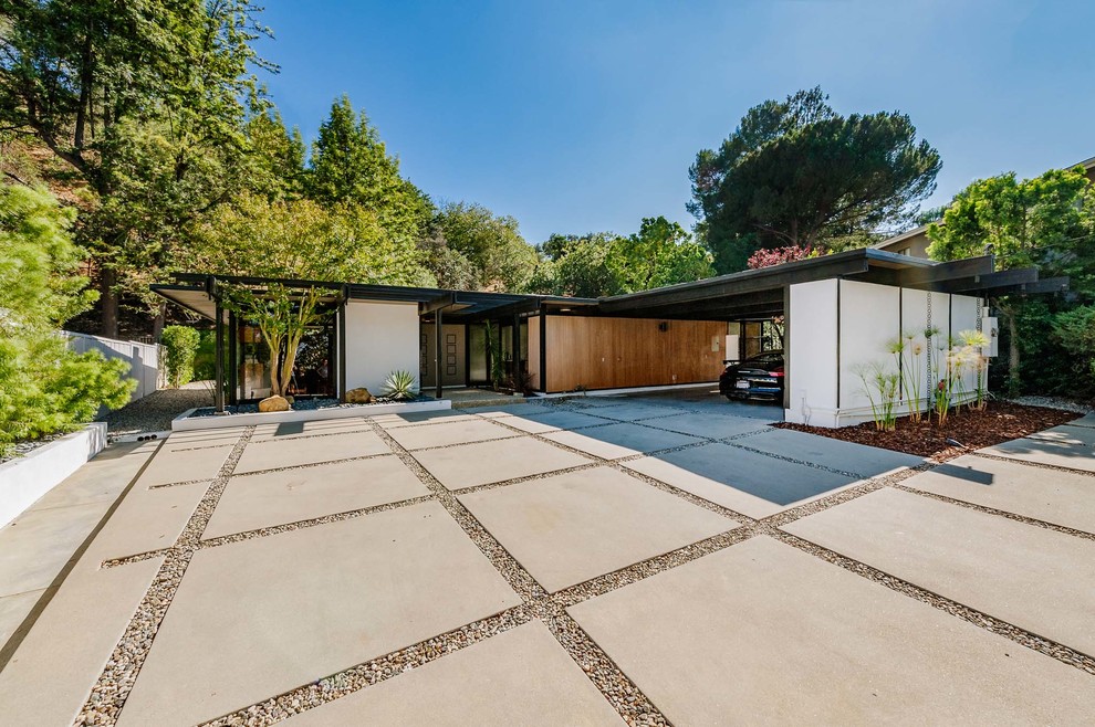 Photo of a large midcentury front yard full sun driveway in Los Angeles with concrete pavers.