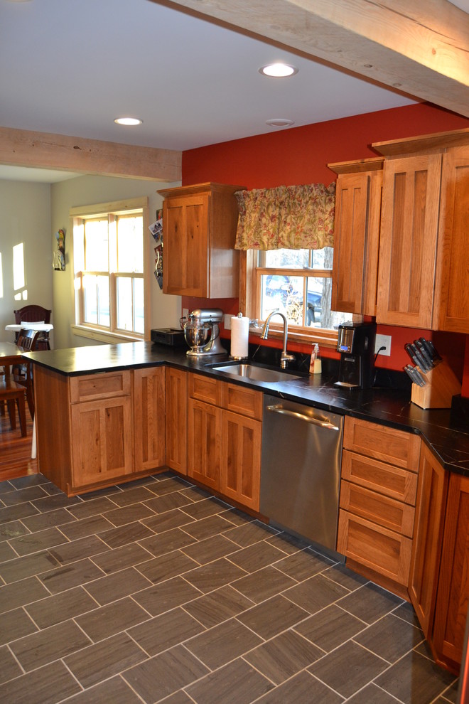 Example of a mid-sized mountain style l-shaped slate floor eat-in kitchen design in Burlington with an undermount sink, shaker cabinets, distressed cabinets, soapstone countertops, stainless steel appliances and a peninsula