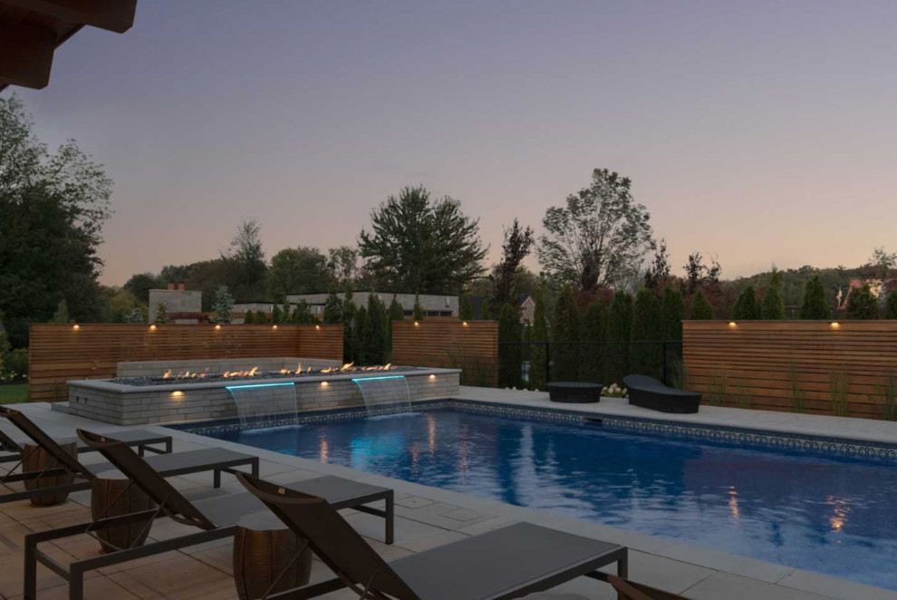 Large contemporary backyard rectangular lap pool in Toronto with a water feature and concrete pavers.