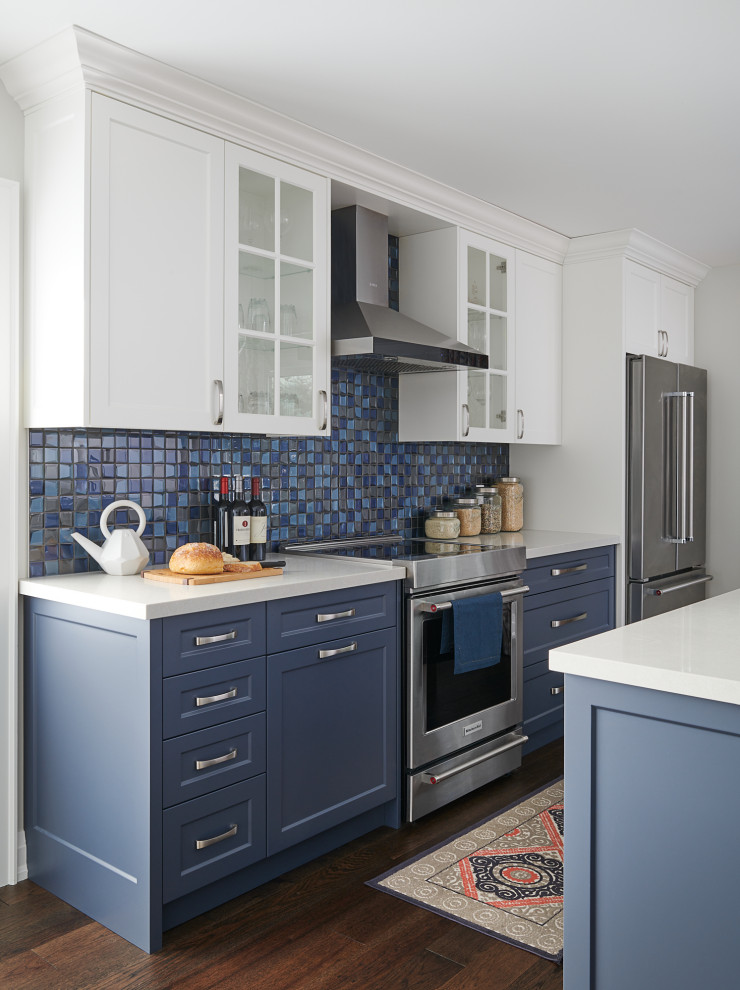 Large traditional eat-in kitchen in Toronto with shaker cabinets, white cabinets, granite benchtops, blue splashback, stainless steel appliances, medium hardwood floors, with island, brown floor and white benchtop.