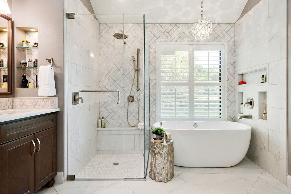 This is an example of a transitional master bathroom in Tampa with recessed-panel cabinets, dark wood cabinets, a freestanding tub, a corner shower, white tile, grey walls, an undermount sink, white floor and a hinged shower door.
