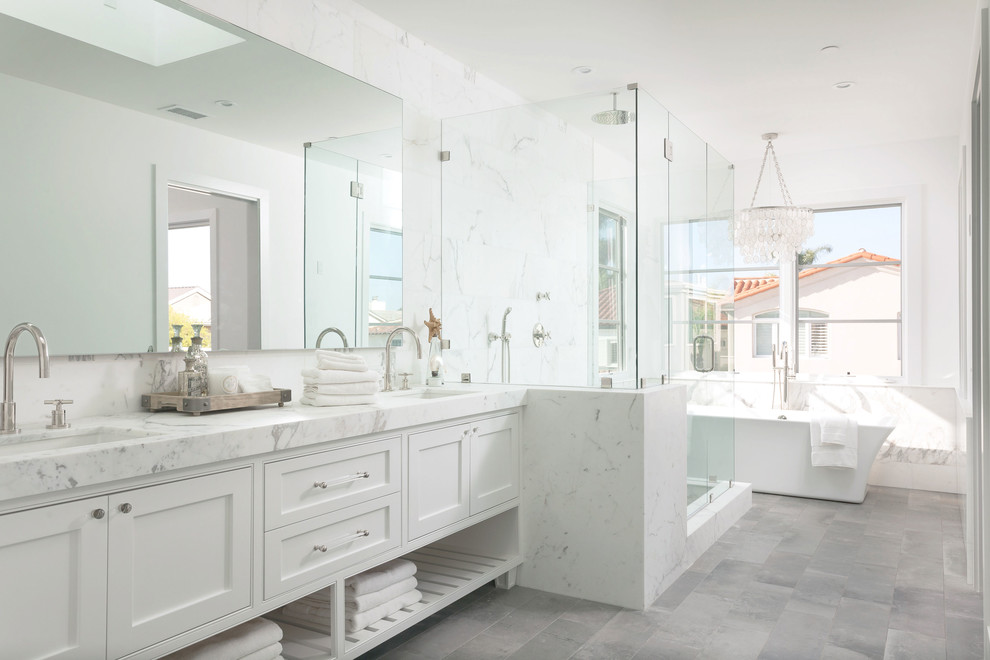 Photo of a beach style master bathroom in Orange County with an undermount sink, white cabinets, a freestanding tub, a corner shower, white tile, white walls and shaker cabinets.