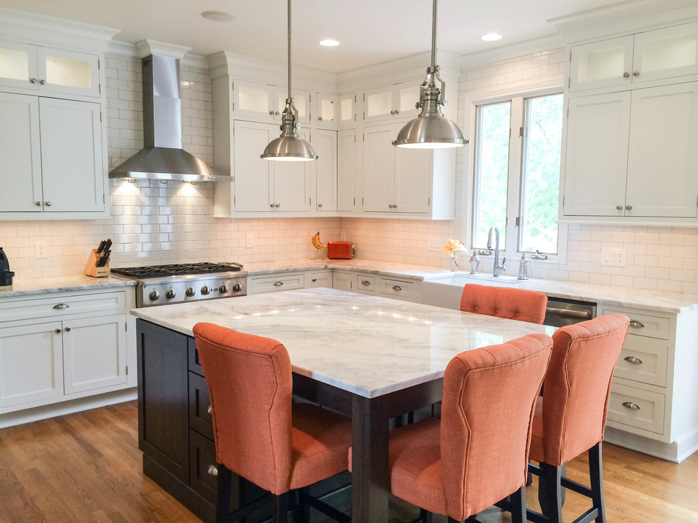 Inspiration for a mid-sized transitional u-shaped eat-in kitchen in Cincinnati with a farmhouse sink, recessed-panel cabinets, white cabinets, quartzite benchtops, white splashback, subway tile splashback, stainless steel appliances, light hardwood floors and with island.