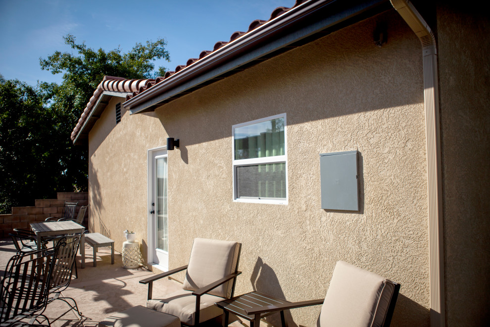 This is an example of a small modern one-storey stucco beige exterior in Los Angeles with a tile roof and a red roof.