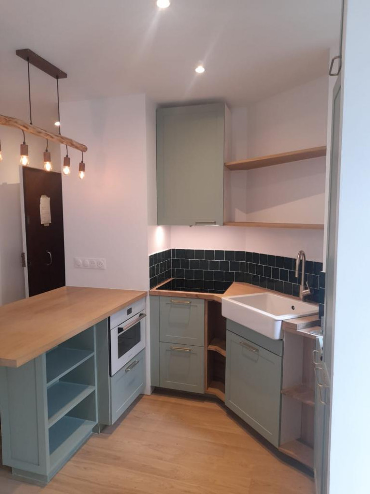 This is an example of a mid-sized modern l-shaped eat-in kitchen in Paris with an undermount sink, recessed-panel cabinets, turquoise cabinets, wood benchtops, green splashback, ceramic splashback, panelled appliances, medium hardwood floors, multiple islands, brown floor and multi-coloured benchtop.
