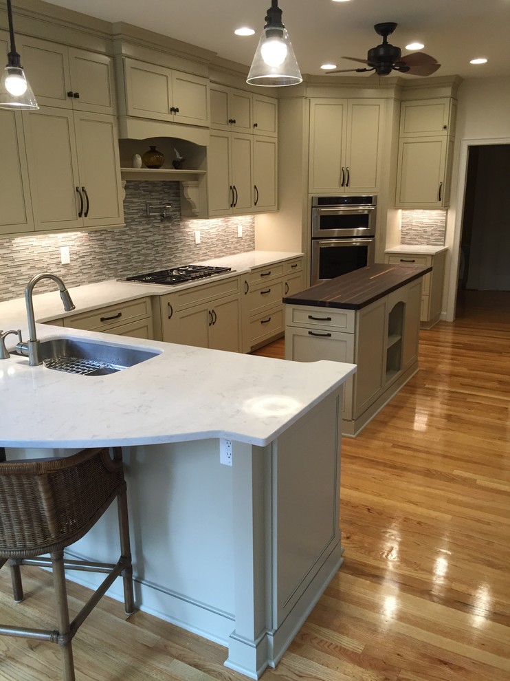 Inspiration for a transitional l-shaped enclosed kitchen remodel with an undermount sink, flat-panel cabinets, quartzite countertops, matchstick tile backsplash, stainless steel appliances and an island