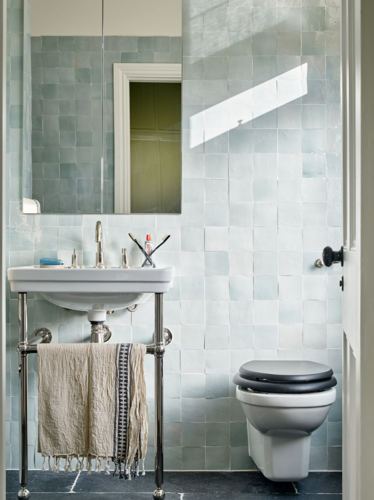 Small transitional master blue tile and porcelain tile marble floor, black floor and single-sink bathroom photo in London with a wall-mount toilet, blue walls, a pedestal sink, a niche and a freestanding vanity