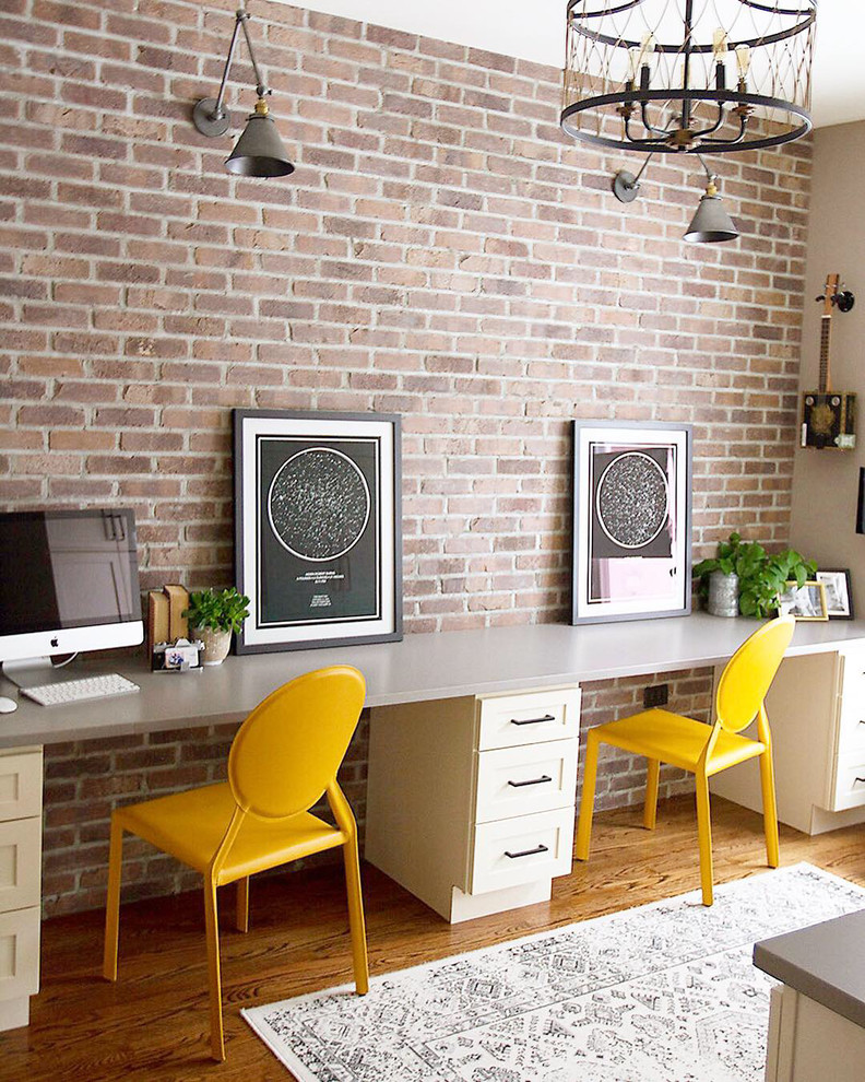 This is an example of a mid-sized industrial home studio in Chicago with beige walls, medium hardwood floors and a built-in desk.