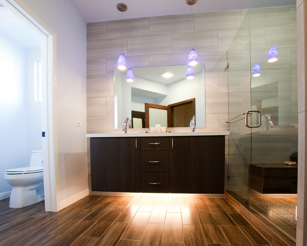 This is an example of a mid-sized contemporary 3/4 bathroom in Orange County with an undermount sink, flat-panel cabinets, dark wood cabinets, engineered quartz benchtops, an alcove shower, a two-piece toilet, gray tile, blue walls and porcelain floors.