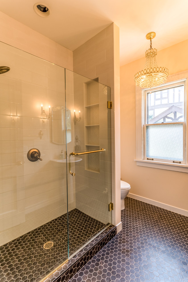 This is an example of a mid-sized transitional 3/4 bathroom in Minneapolis with an alcove shower, a one-piece toilet, beige walls, porcelain floors, a pedestal sink, black floor and a hinged shower door.