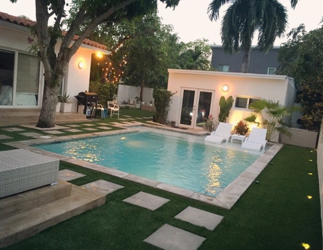 Mid-sized beach style backyard l-shaped lap pool in Miami with stamped concrete.