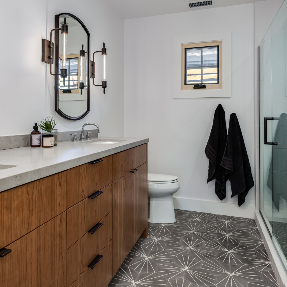 Medium sized classic family bathroom in Orange County with flat-panel cabinets, an alcove shower, a one-piece toilet, white tiles, ceramic tiles, white walls, cement flooring, a submerged sink, engineered stone worktops, grey floors, a hinged door, grey worktops, double sinks, a built in vanity unit and medium wood cabinets.