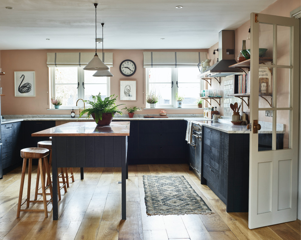 Urige Wohnküche mit Doppelwaschbecken, schwarzen Schränken, Kupfer-Arbeitsplatte, Rückwand aus Marmor, Elektrogeräten mit Frontblende, hellem Holzboden und Kücheninsel in Hertfordshire
