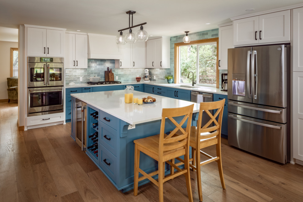 Inspiration for a mid-sized arts and crafts u-shaped eat-in kitchen in Other with an undermount sink, recessed-panel cabinets, blue cabinets, quartzite benchtops, blue splashback, glass tile splashback, stainless steel appliances, medium hardwood floors, with island, brown floor, beige benchtop and exposed beam.