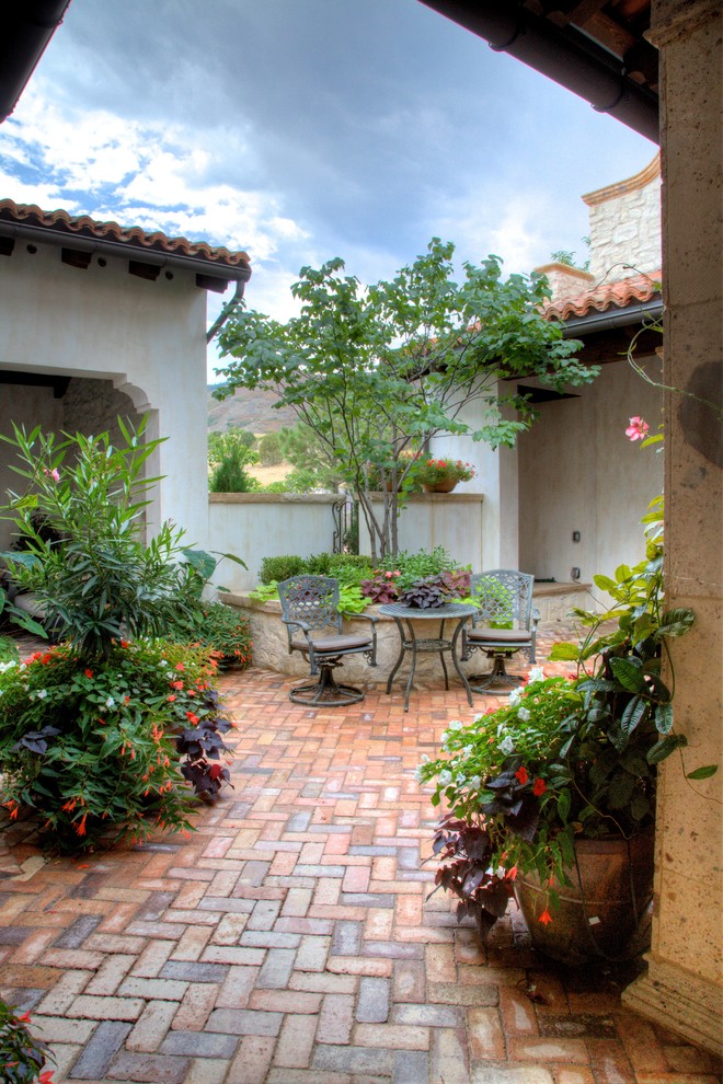 Inspiration for a large mediterranean courtyard patio in Denver with a container garden and gravel.