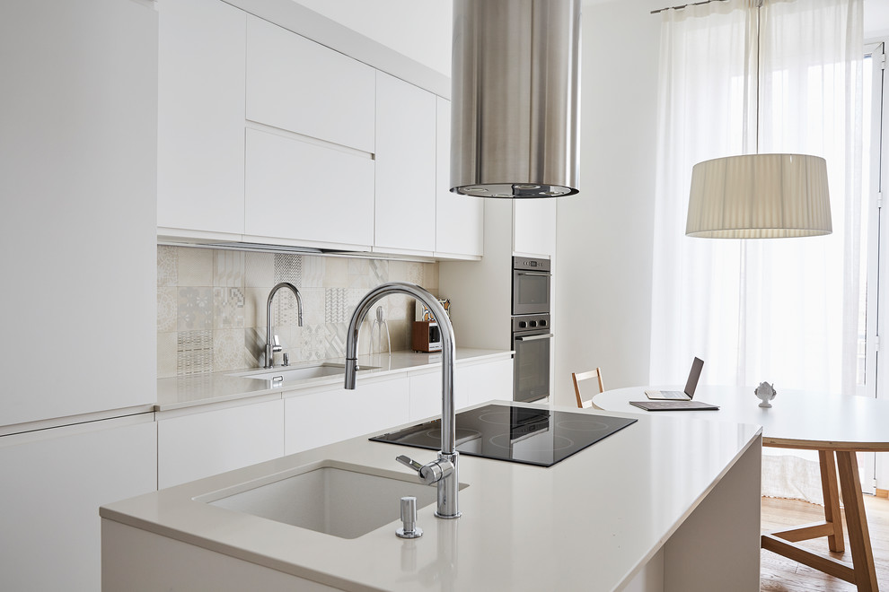 Mid-sized contemporary single-wall eat-in kitchen in Milan with an undermount sink, flat-panel cabinets, white cabinets, quartz benchtops, multi-coloured splashback, mosaic tile splashback, stainless steel appliances, medium hardwood floors, with island and beige floor.