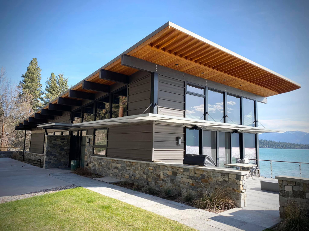 Inspiration pour une façade de maison métallique et marron minimaliste de taille moyenne et à un étage avec un toit en appentis, un toit en métal et un toit gris.