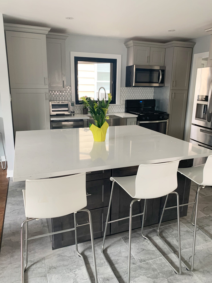 This is an example of a small contemporary u-shaped eat-in kitchen in New York with a farmhouse sink, recessed-panel cabinets, grey cabinets, quartz benchtops, white splashback, ceramic splashback, stainless steel appliances, ceramic floors, with island, grey floor and white benchtop.