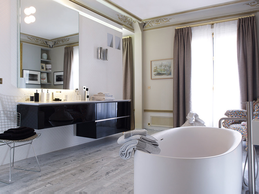 Inspiration for a contemporary bathroom in London with a freestanding tub, gray tile, white walls and marble floors.