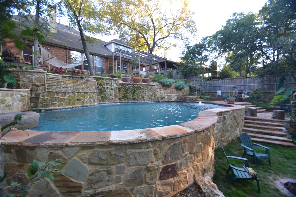 Design ideas for a large country backyard custom-shaped natural pool in Dallas with a water feature and natural stone pavers.