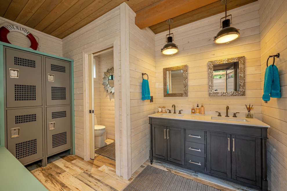 Inspiration for an expansive arts and crafts bathroom in Seattle with brown cabinets, a one-piece toilet, beige walls, light hardwood floors, an integrated sink, marble benchtops, white benchtops, an enclosed toilet, a double vanity, a freestanding vanity, wood and planked wall panelling.