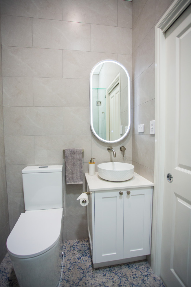 Foto på ett litet funkis vit badrum, med skåp i shakerstil, vita skåp, en toalettstol med hel cisternkåpa, beige kakel, cementkakel, beige väggar, cementgolv, ett fristående handfat, bänkskiva i kvarts, blått golv och dusch med gångjärnsdörr