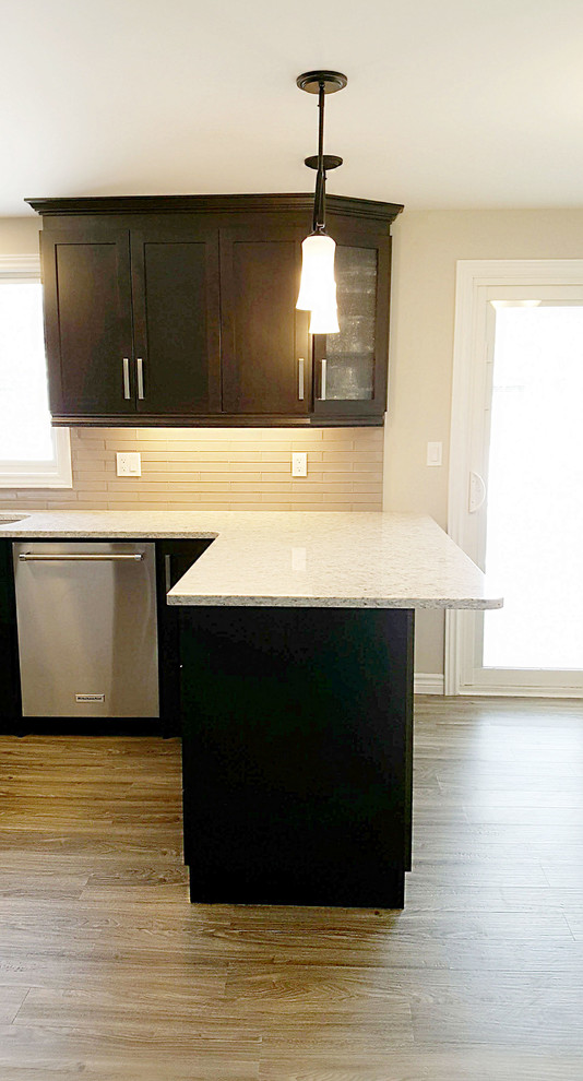 Example of a large transitional l-shaped vinyl floor and brown floor eat-in kitchen design in Toronto with an undermount sink, recessed-panel cabinets, dark wood cabinets, quartzite countertops, beige backsplash, glass tile backsplash and white countertops