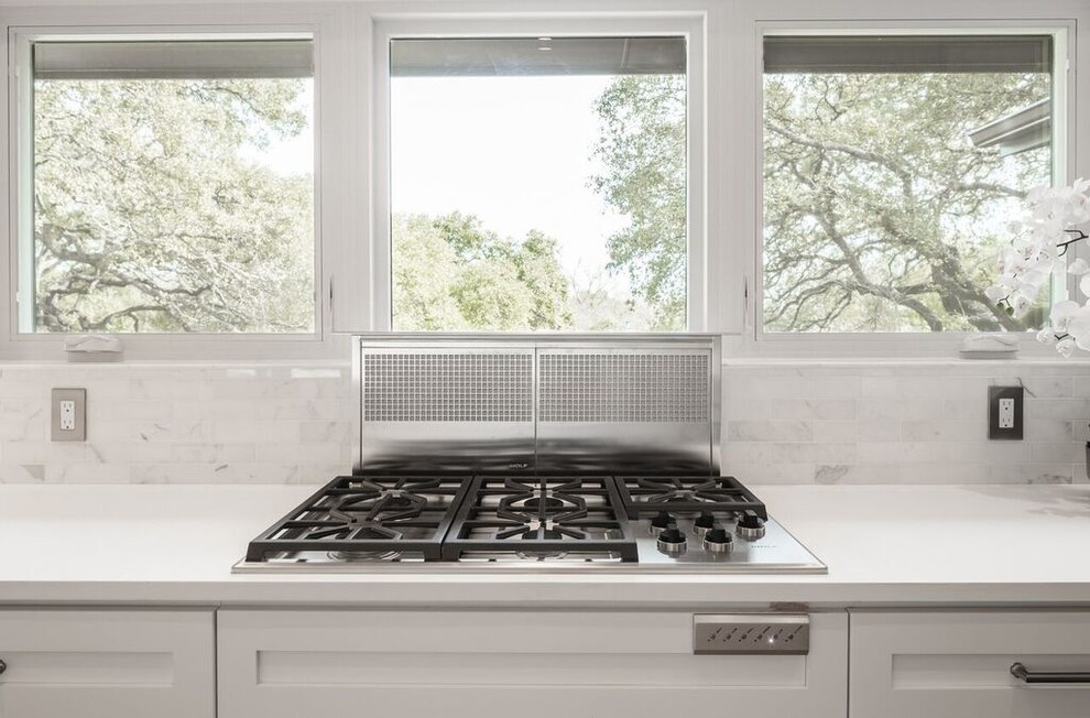 Enclosed kitchen - transitional u-shaped enclosed kitchen idea in Austin with shaker cabinets, white cabinets, quartz countertops, white backsplash, stone tile backsplash, stainless steel appliances and a peninsula