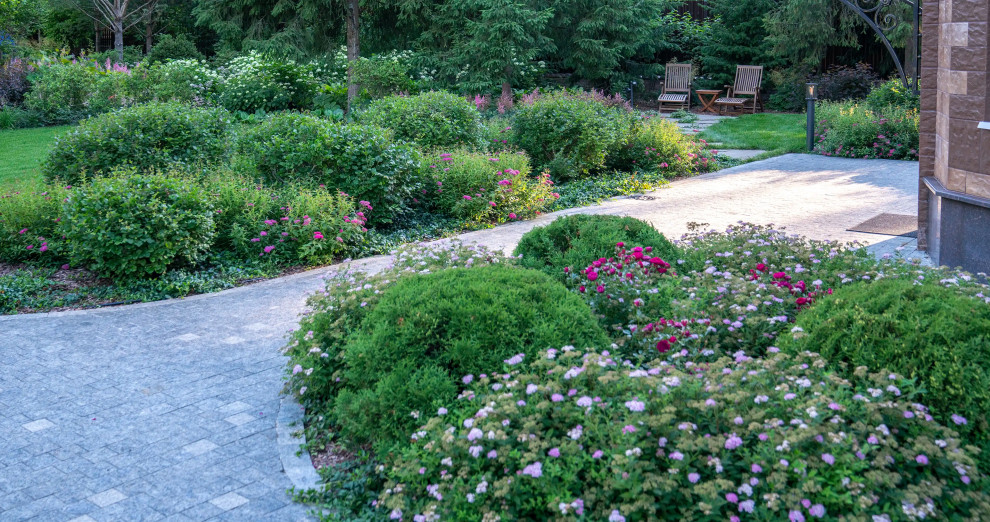 На фото: большой летний участок и сад на заднем дворе в стиле кантри с клумбами, полуденной тенью, покрытием из каменной брусчатки и с металлическим забором с