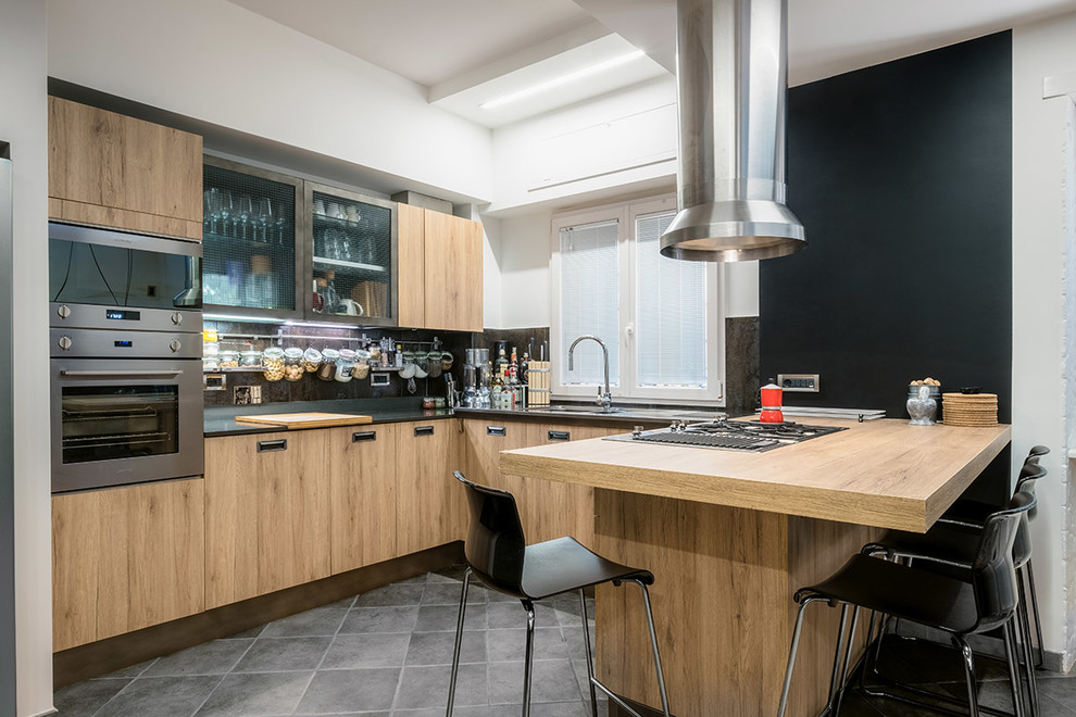 Small industrial u-shaped open plan kitchen in Rome with flat-panel cabinets, medium wood cabinets, a peninsula, an undermount sink, marble benchtops, stainless steel appliances, porcelain floors, grey floor, black benchtop, black splashback and marble splashback.
