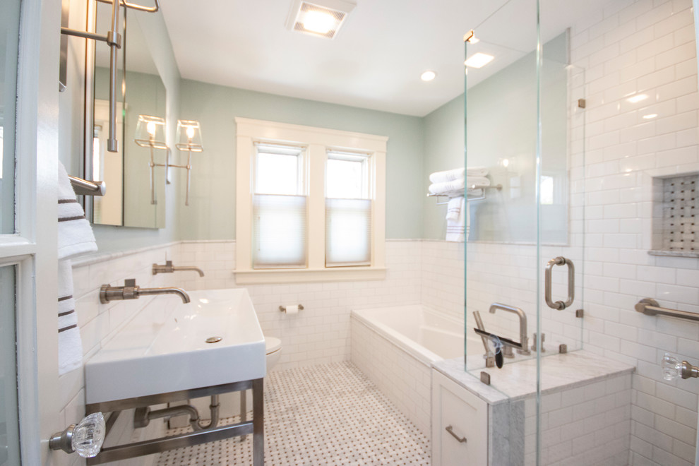 Design ideas for a mid-sized transitional master bathroom in Providence with shaker cabinets, white cabinets, a drop-in tub, a corner shower, a one-piece toilet, white tile, porcelain tile, blue walls, mosaic tile floors, a console sink, multi-coloured floor, a hinged shower door and white benchtops.