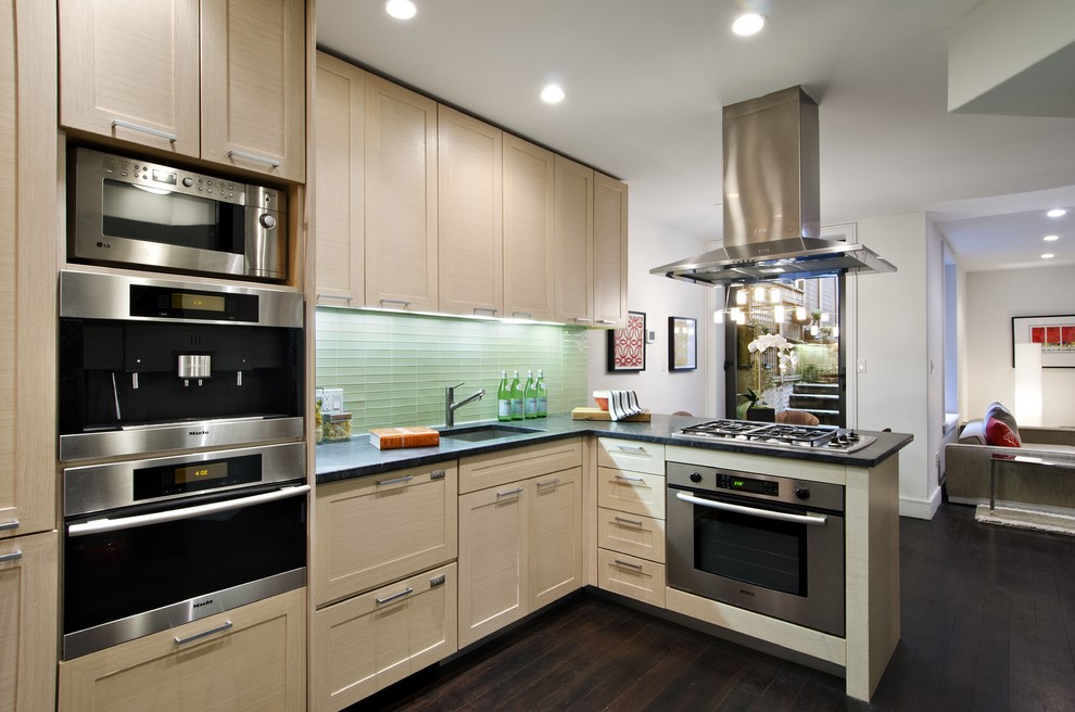 This is an example of a contemporary kitchen in New York with glass tile splashback, stainless steel appliances, green splashback, shaker cabinets and light wood cabinets.