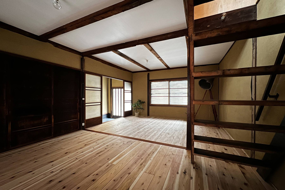 На фото: маленькая открытая гостиная комната с коричневыми стенами, светлым паркетным полом, коричневым полом, балками на потолке и акцентной стеной для на участке и в саду