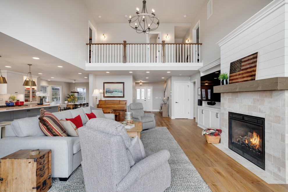 This is an example of an expansive farmhouse open plan living room in Portland with grey walls, medium hardwood flooring, a standard fireplace, a stacked stone fireplace surround, a built-in media unit, brown floors and a vaulted ceiling.