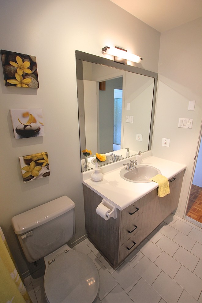 Mid-sized modern 3/4 bathroom in Montreal with flat-panel cabinets, light wood cabinets, an alcove tub, a shower/bathtub combo, a two-piece toilet, white tile, ceramic tile, beige walls, ceramic floors, a drop-in sink, laminate benchtops, grey floor and a shower curtain.