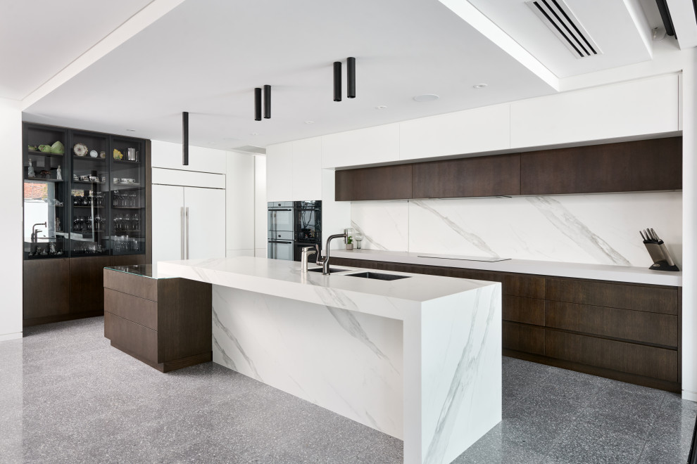 Inspiration for an expansive contemporary l-shaped eat-in kitchen in Perth with an undermount sink, flat-panel cabinets, white cabinets, quartz benchtops, white splashback, porcelain splashback, black appliances, concrete floors, with island, grey floor and white benchtop.