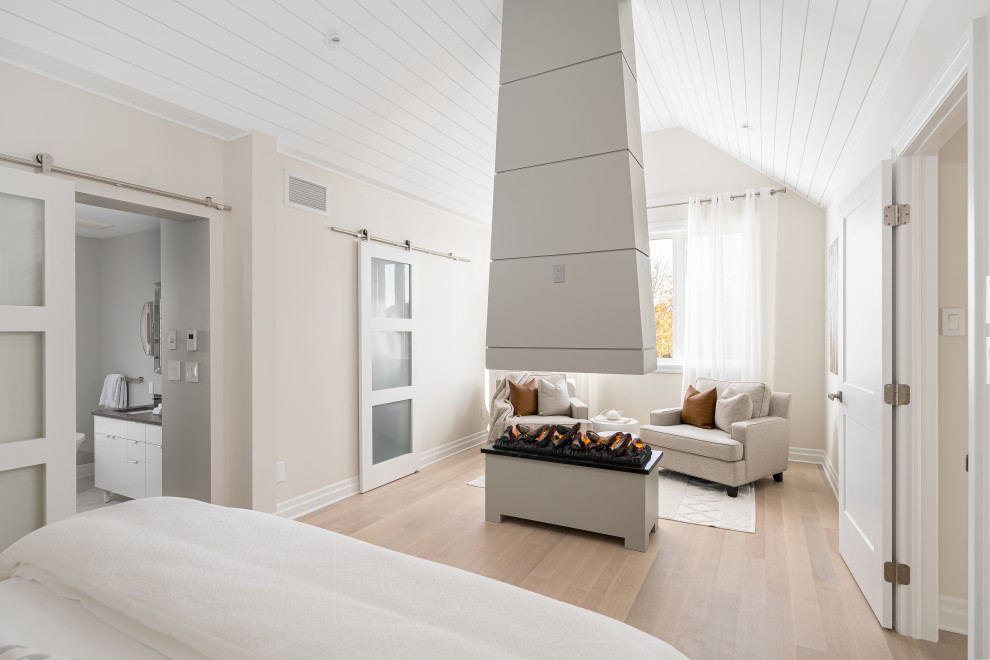 This is an example of a large contemporary master bedroom in Montreal with beige walls, light hardwood floors, a two-sided fireplace and timber.
