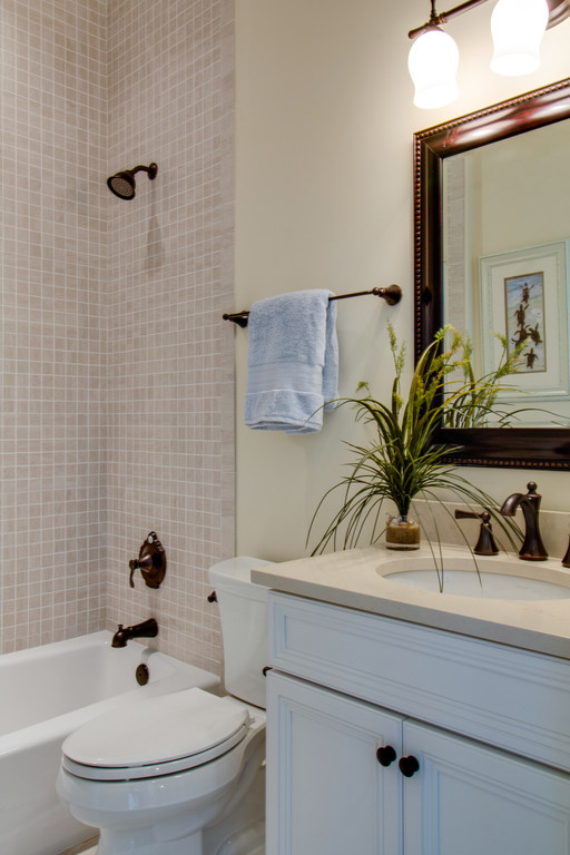 This is an example of a mid-sized traditional bathroom in Other with white cabinets, a shower/bathtub combo, beige tile, mosaic tile, beige walls, ceramic floors, an undermount sink, beige floor and beige benchtops.