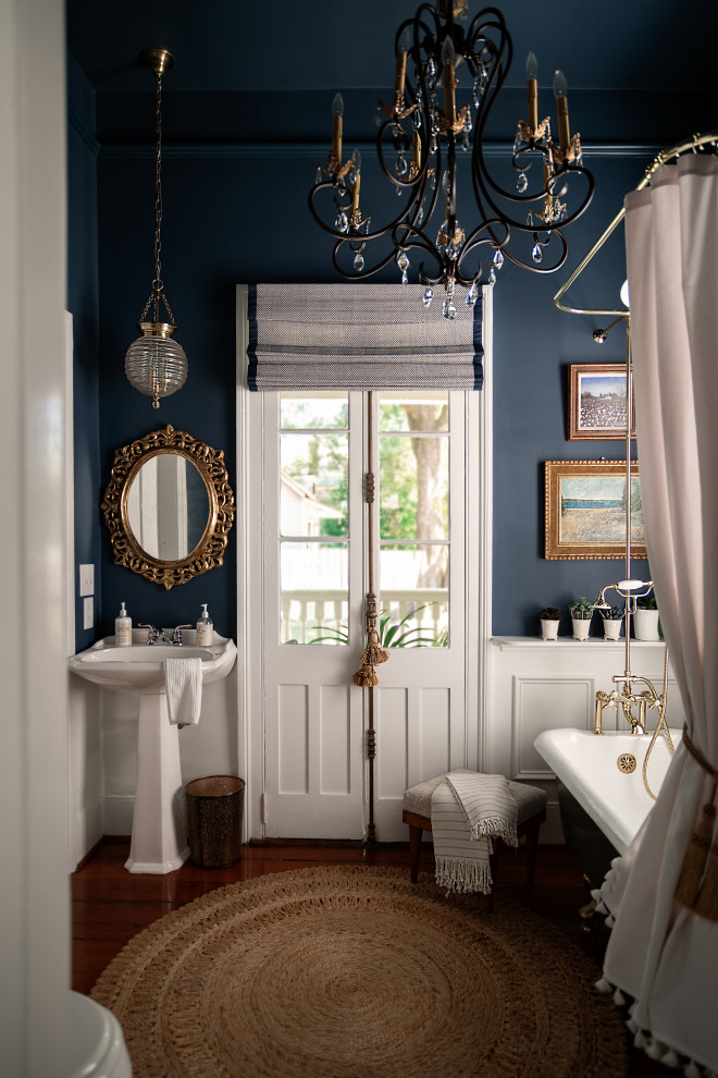 Стильный дизайн: ванная комната в классическом стиле с ванной на ножках, синими стенами, темным паркетным полом, раковиной с пьедесталом, коричневым полом, шторкой для ванной и тумбой под одну раковину - последний тренд