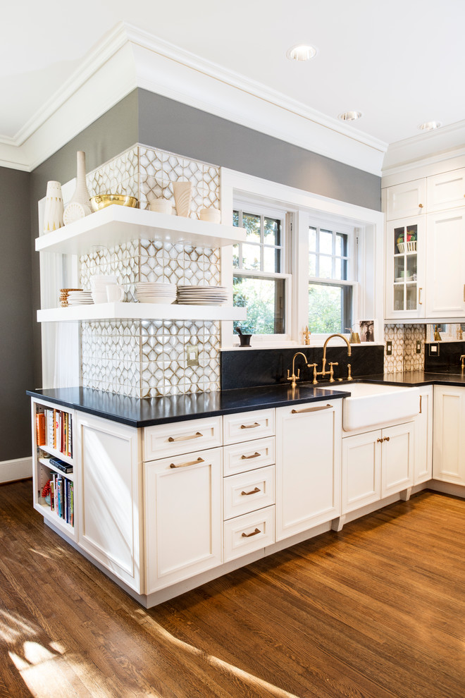 Large transitional u-shaped eat-in kitchen in Other with a farmhouse sink, white splashback, glass tile splashback, medium hardwood floors, with island, brown floor, recessed-panel cabinets, white cabinets, marble benchtops and stainless steel appliances.