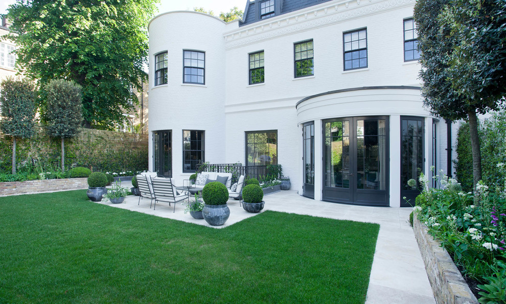 This is an example of a traditional backyard partial sun formal garden in London with a garden path.