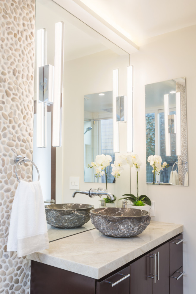Small contemporary master bathroom in Los Angeles with flat-panel cabinets, brown cabinets, a freestanding tub, a curbless shower, a wall-mount toilet, beige tile, pebble tile, beige walls, terrazzo floors, a vessel sink, marble benchtops, beige floor, a sliding shower screen and beige benchtops.