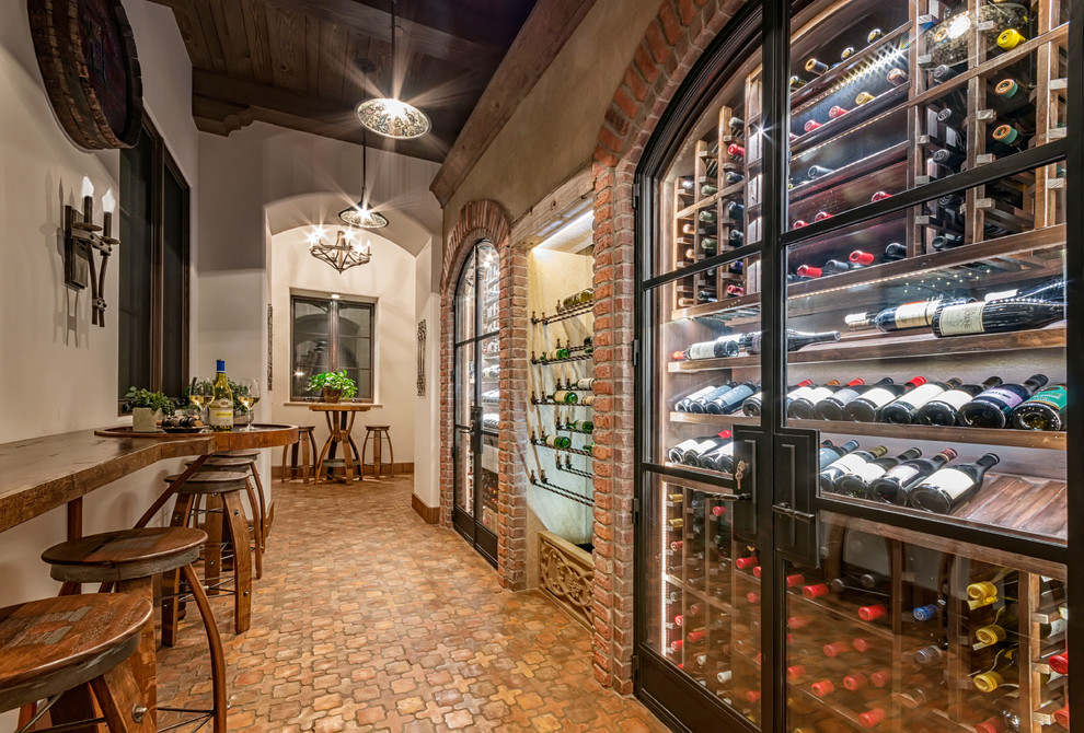 Inspiration for a mediterranean wine cellar in San Diego with terra-cotta floors, storage racks and brown floor.