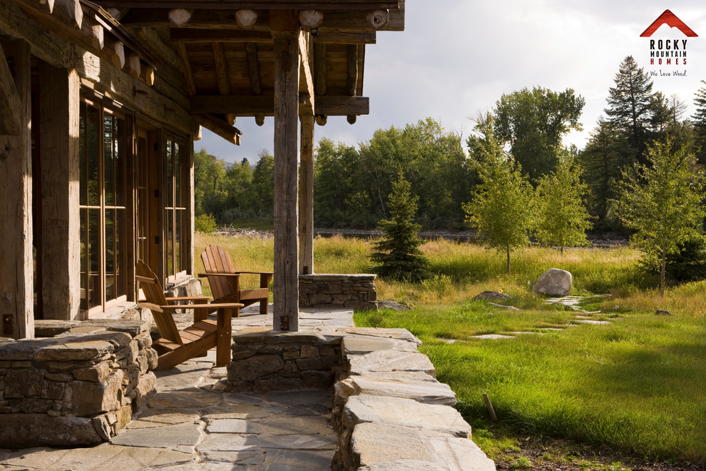 This is an example of a mid-sized country side yard patio in Other with natural stone pavers and a roof extension.