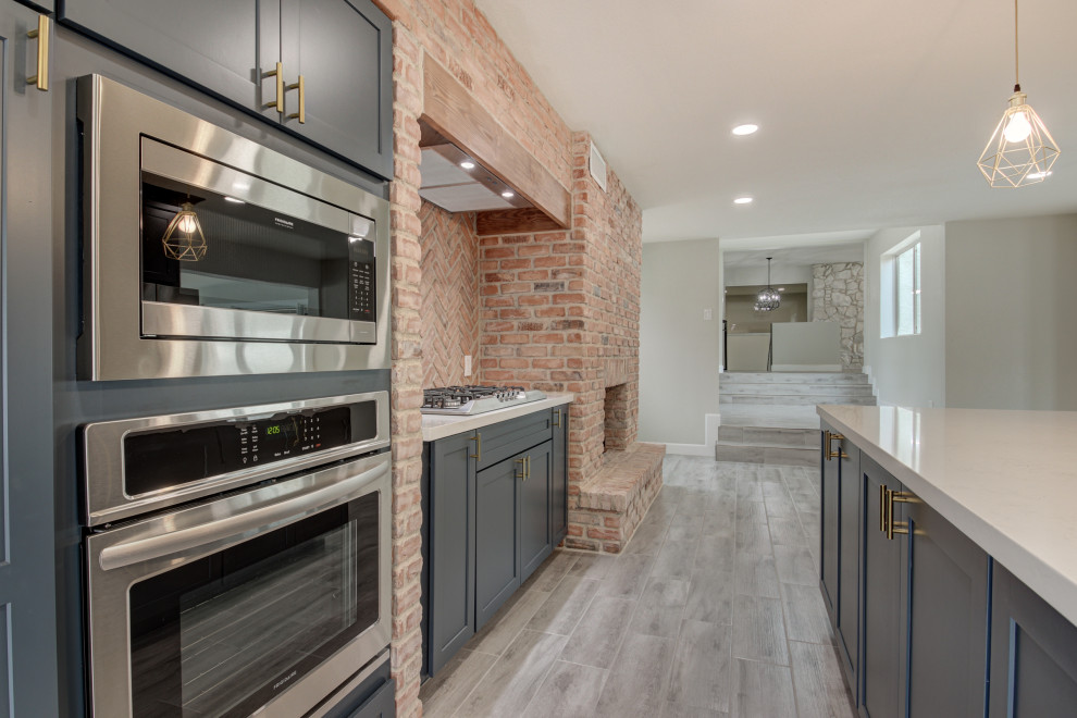 Example of a mid-sized transitional u-shaped porcelain tile and gray floor eat-in kitchen design in Phoenix with a farmhouse sink, shaker cabinets, blue cabinets, quartz countertops, red backsplash, brick backsplash, stainless steel appliances, an island and white countertops